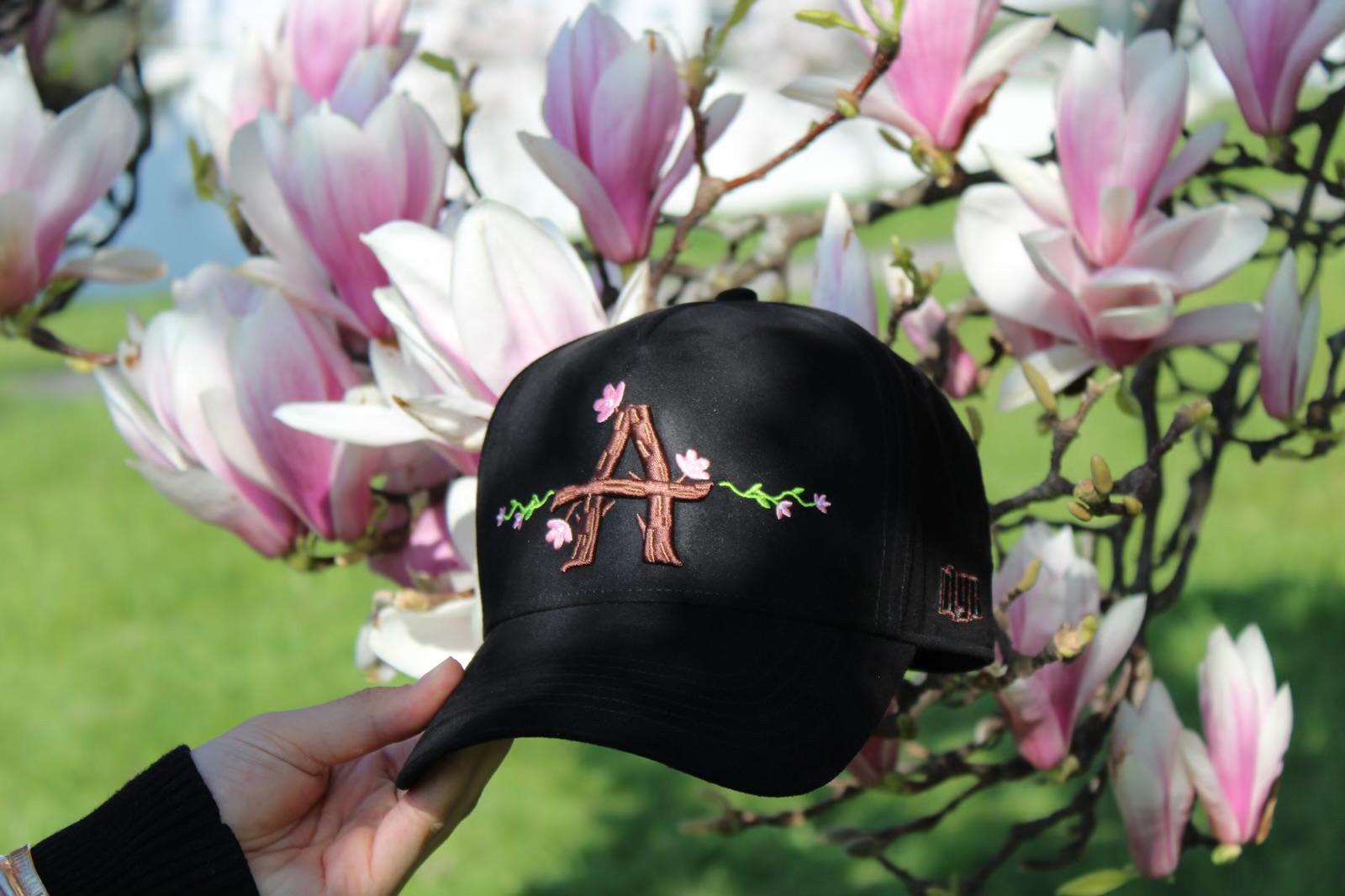 Casquette Alvona tenue devant des fleurs de magnolia