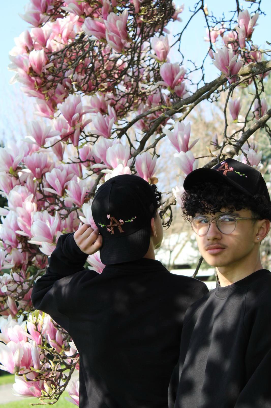 Navid ajustant sa casquette Alvona devant des magnolias