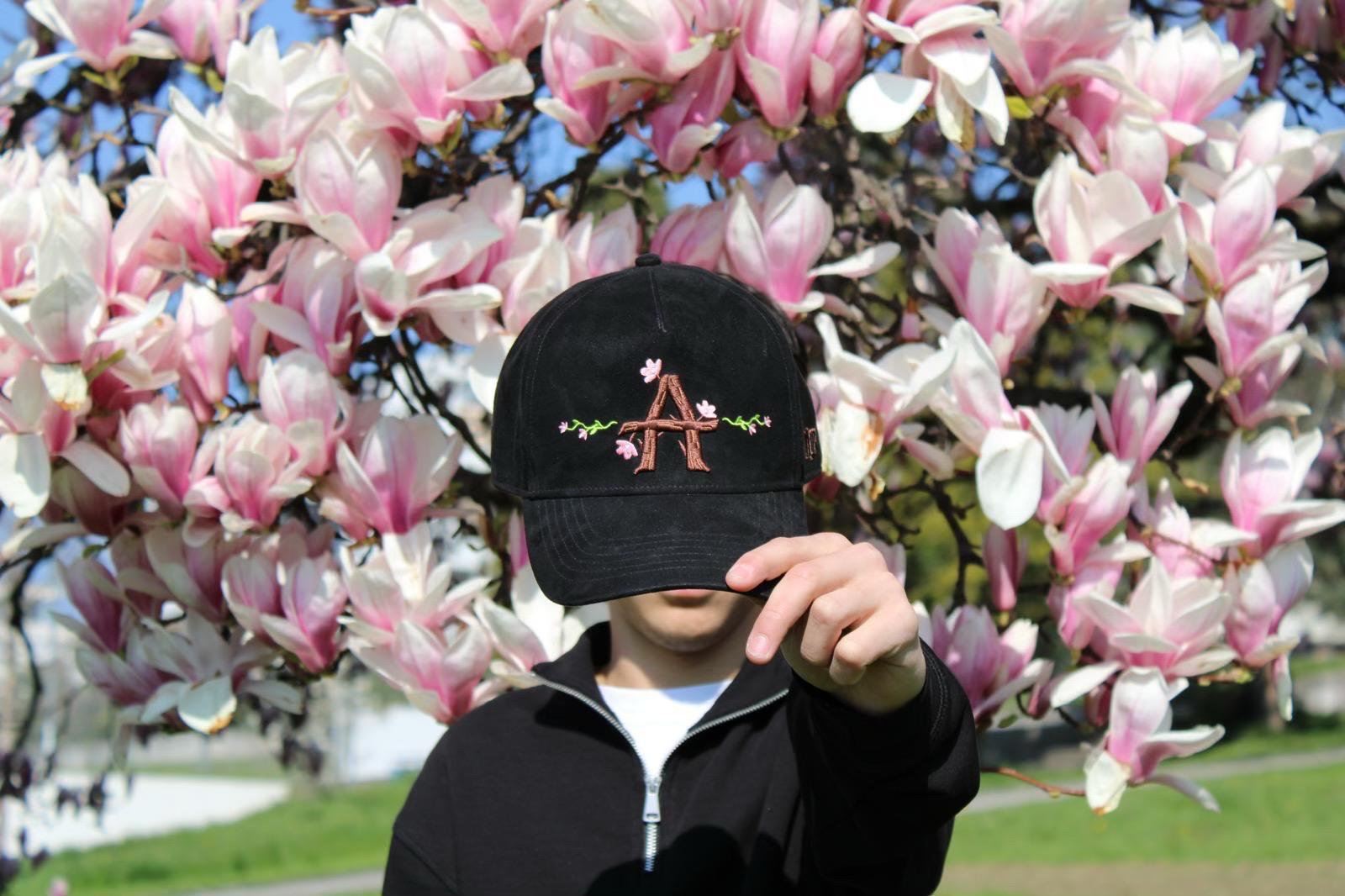 Navid portant la casquette Alvona devant des fleurs de magnolia